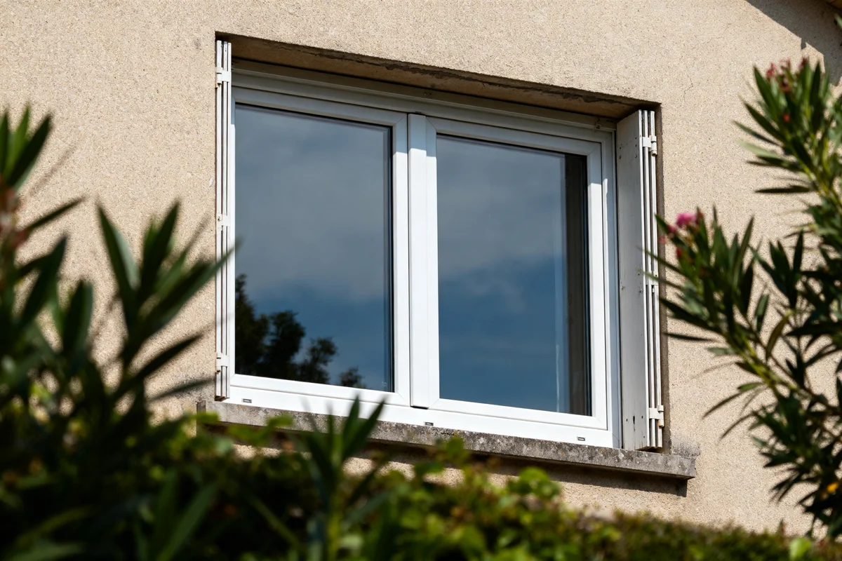 Fenêtre double vitrage prix abordable visible depuis un jardin fleuri en plein soleil