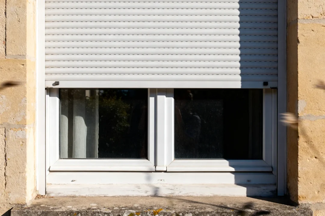 Fenêtre PVC avec volet roulant fermé sur mur en pierre fenêtre pvc prix abordable